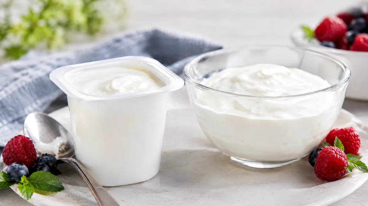 Pot de petit-suisse individuel et bol de fromage blanc accompagnés de framboises